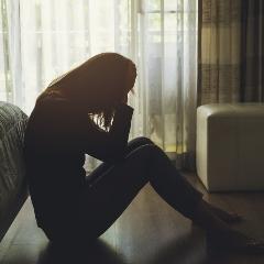 Person sitting on the floor in the dark with head in hands